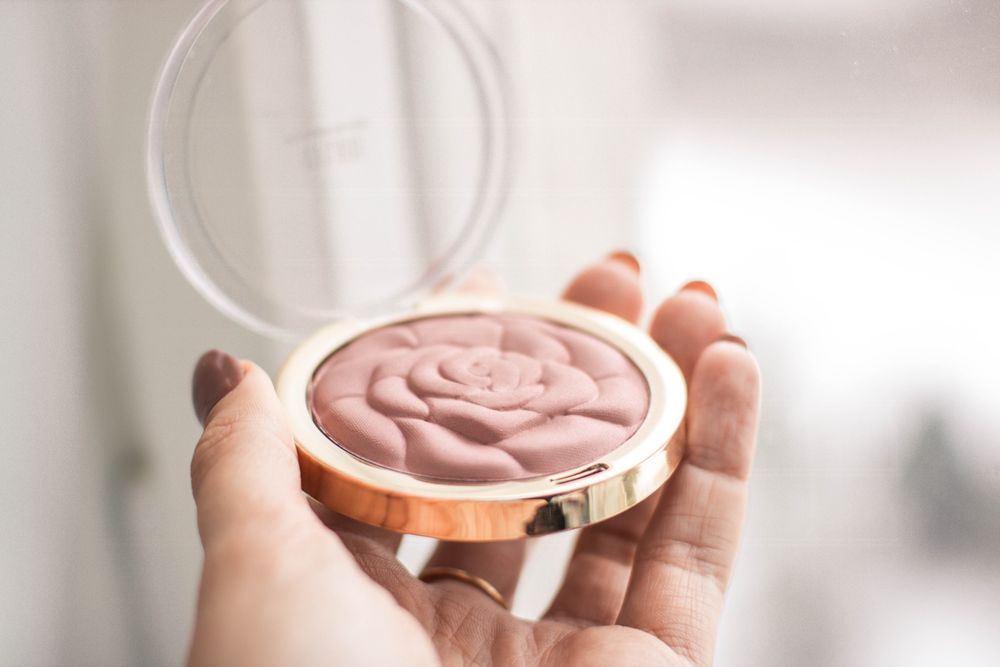 A rose-shaped blush compact held in hand