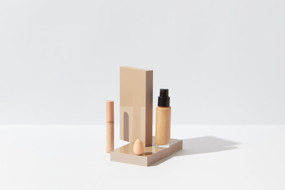 Foundation, concealer and a blending sponge on a clean white surface