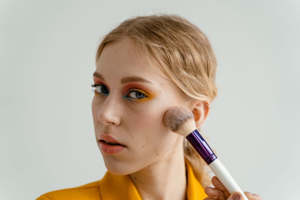 A woman applying blush with a makeup brush